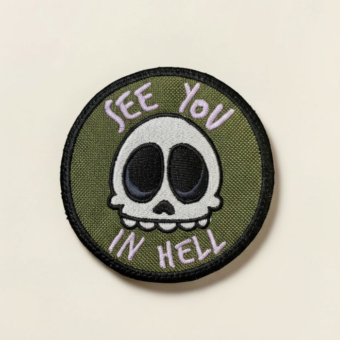 My Threaded Heart embroidered patch with a green background, featuring a white skull with black eyes and purple text saying "See You In Hell".